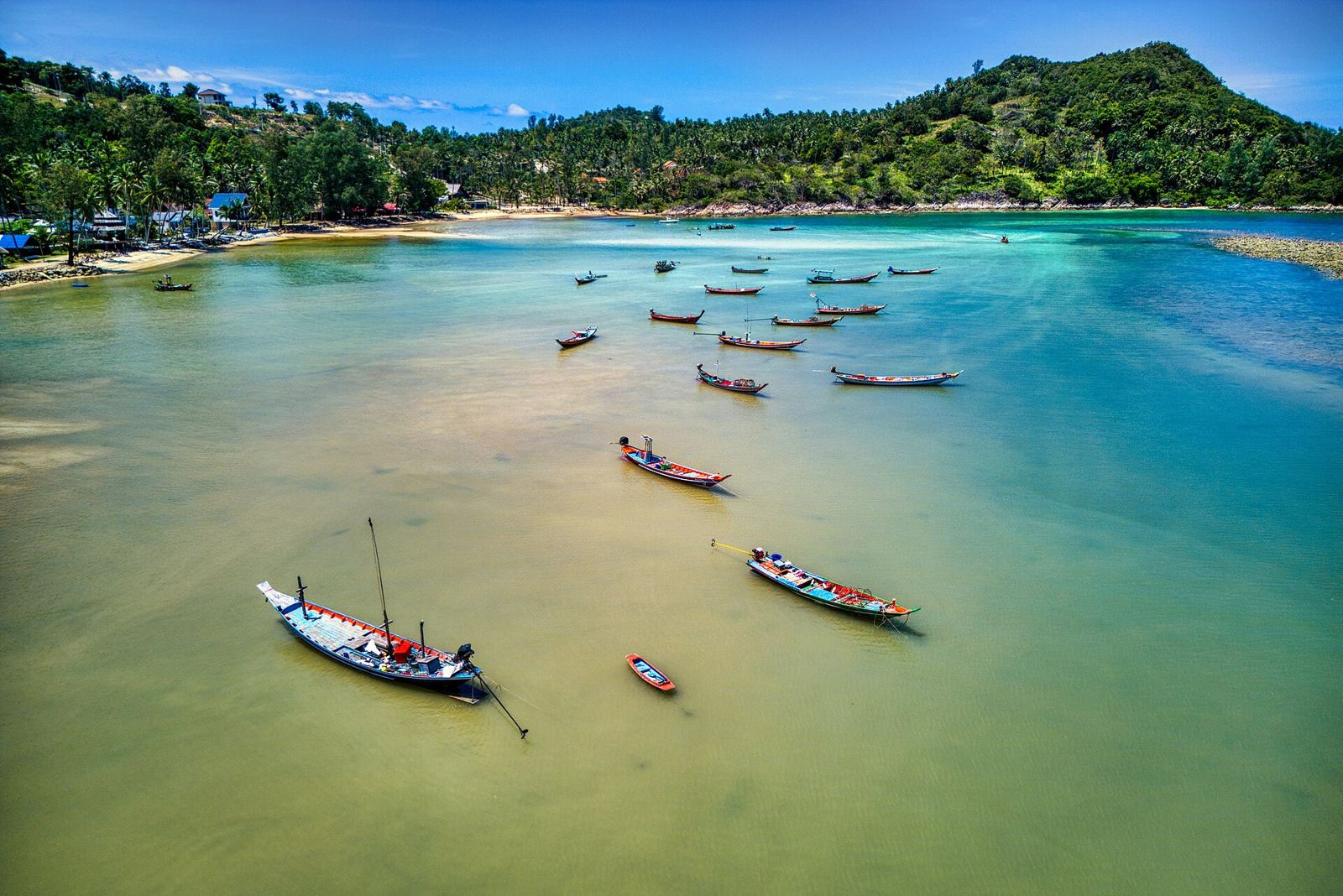 Longtail boats anchored in a shallow bay on Koh Phangan