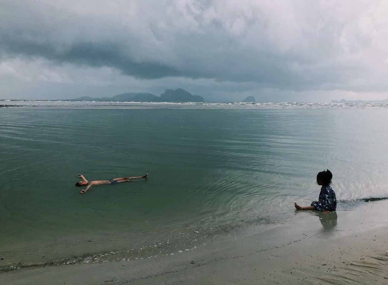 Two children playing in calm, shallow water on a Thai beach