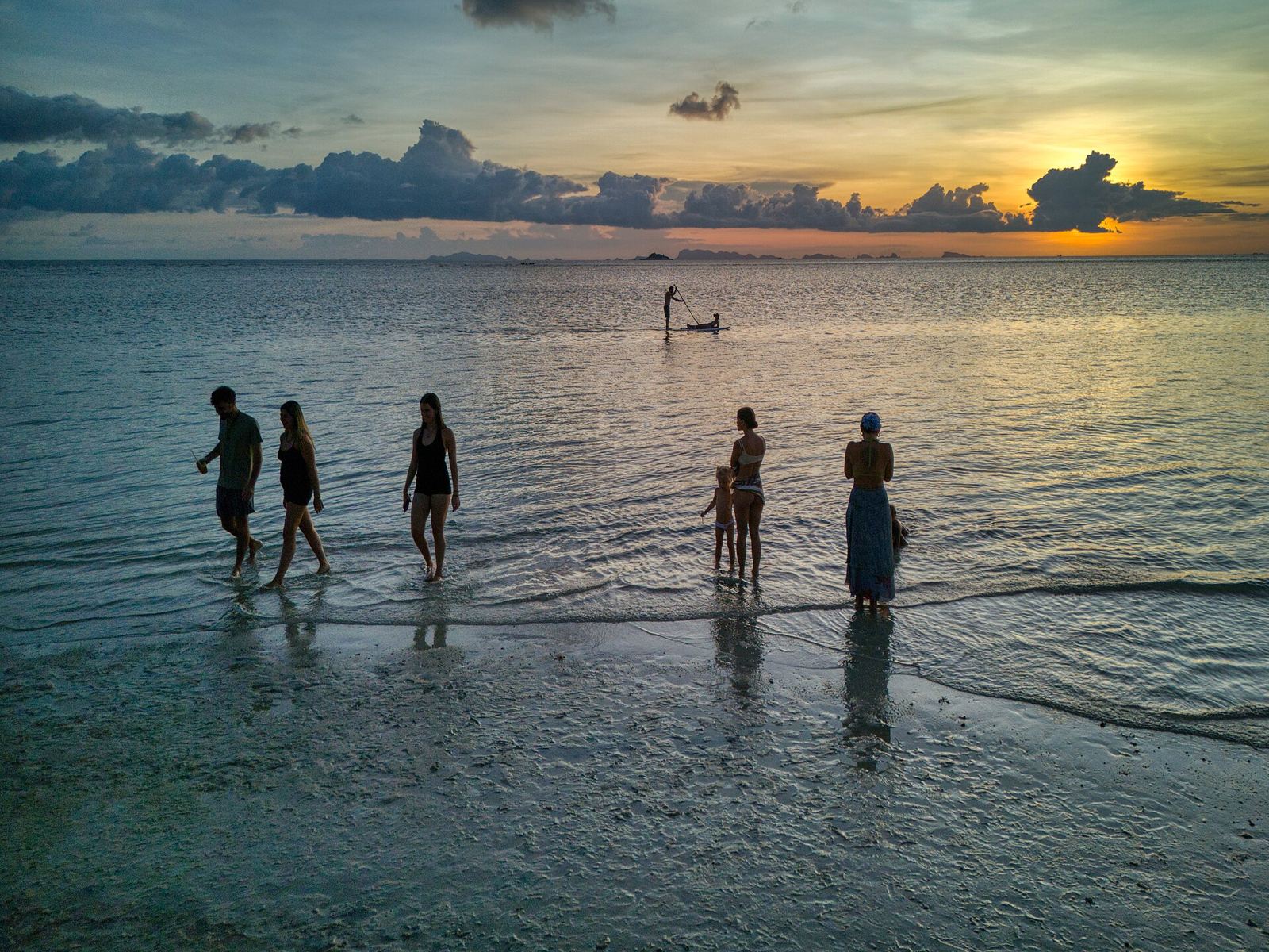 People walking into calm water at dawn on Koh Phangan