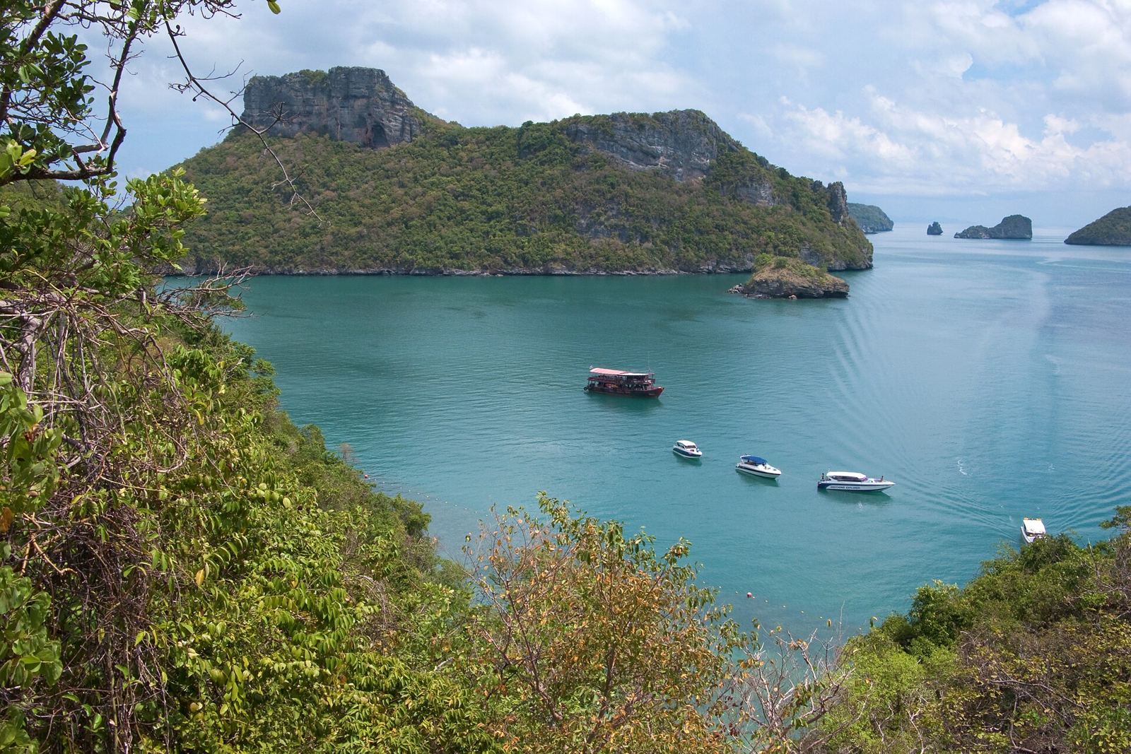 Boats anchored in a turquoise bay between limestone islands in Mu Ko Ang Thong National Marine Park